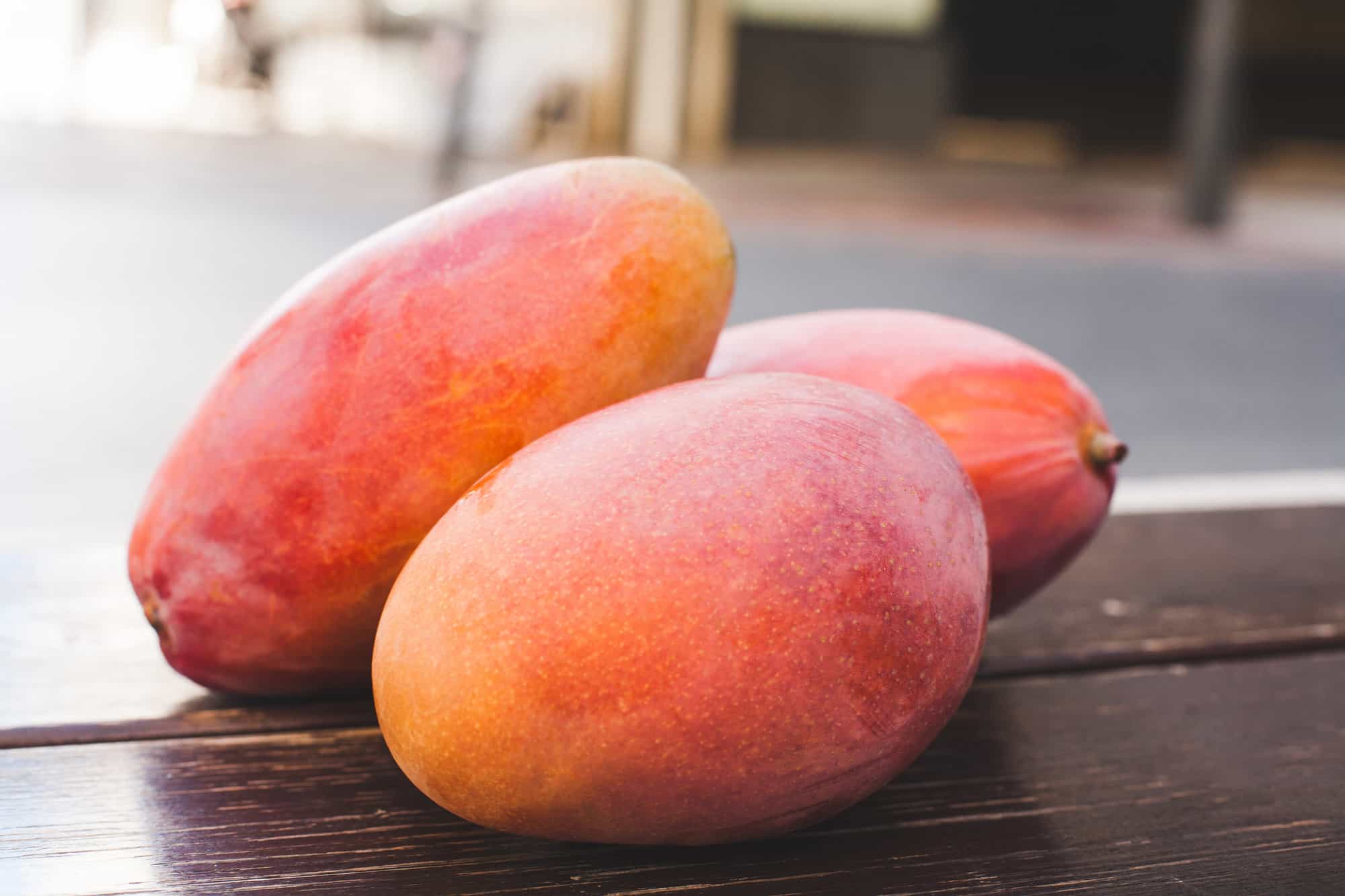 3 mangos sitting on a table.